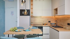 Une cuisine moderne dotée d’un plan de travail en bois, d’appareils électroménagers intégrés et d’un coin repas avec une table et des chaises.