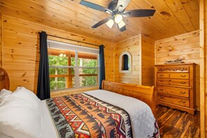 A wooden cabin room with a bed, a dresser, a ceiling fan, and a window with curtains. - Cliffview Resort Lakefront 4BR, 3BTH- No Smoking/Pets. Fishing Dock, Game Rm. (Campton)