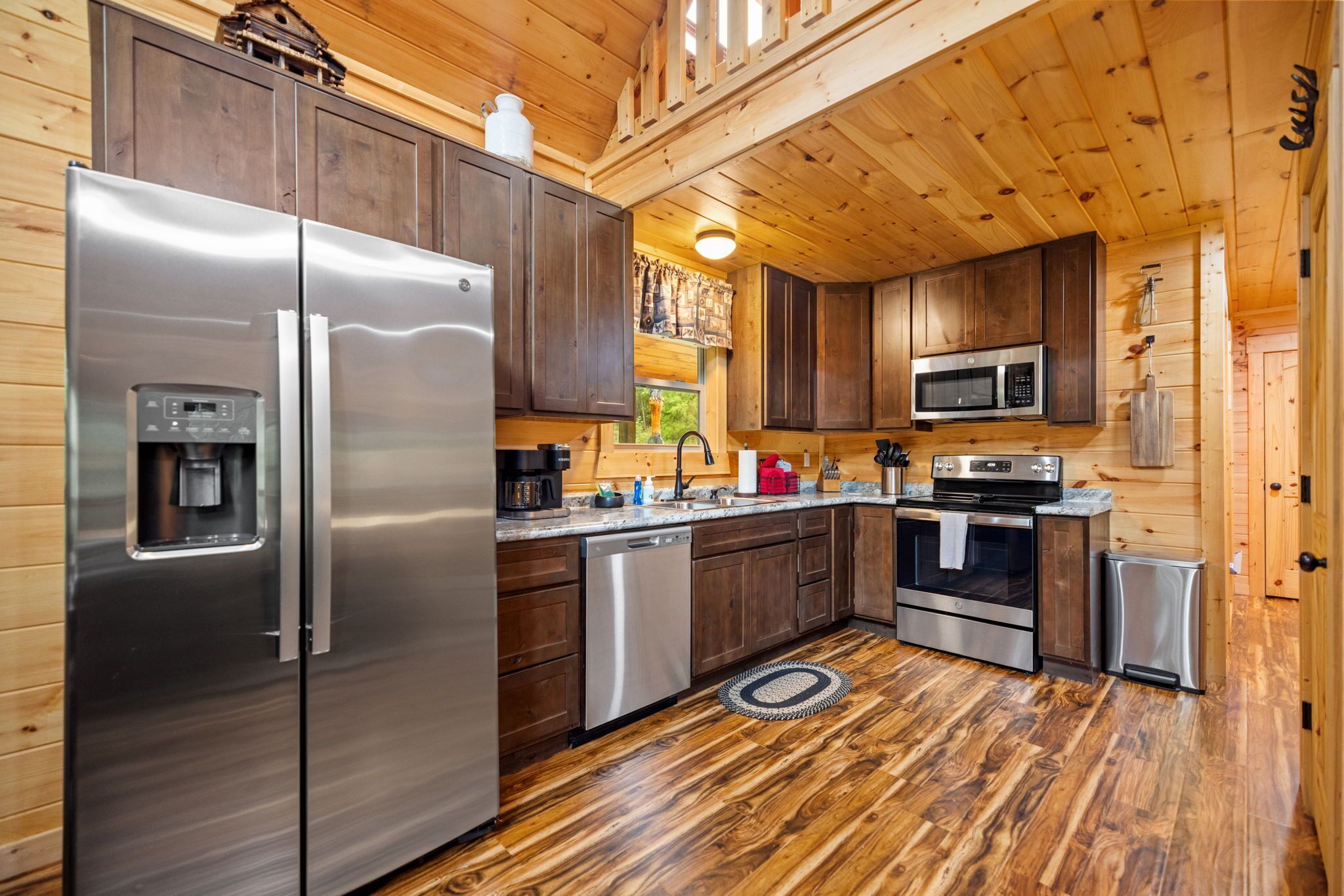 A compact kitchen with stainless steel appliances, wooden cabinets, and a central island.