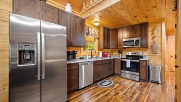 A compact kitchen with stainless steel appliances, wooden cabinets, and a central island.