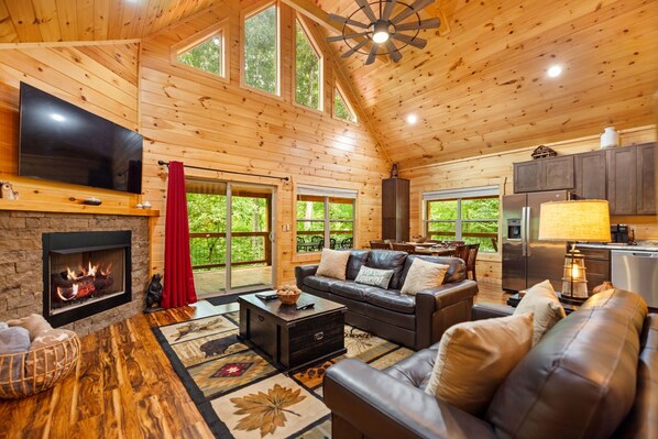 A cozy cabin interior with a fireplace, leather sofa, and a dining area. - Cliffview Resort Lakefront 4BR, 3BTH- No Smoking/Pets. Fishing Dock, Game Rm. (Campton)