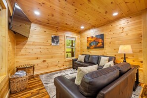 A cozy cabin interior with a sofa, a lamp, a painting, and a window. - Cliffview Resort Lakefront  4BR, 3BTH- No Smoking/Pets. Fishing Dock, Game Rm. (Campton)