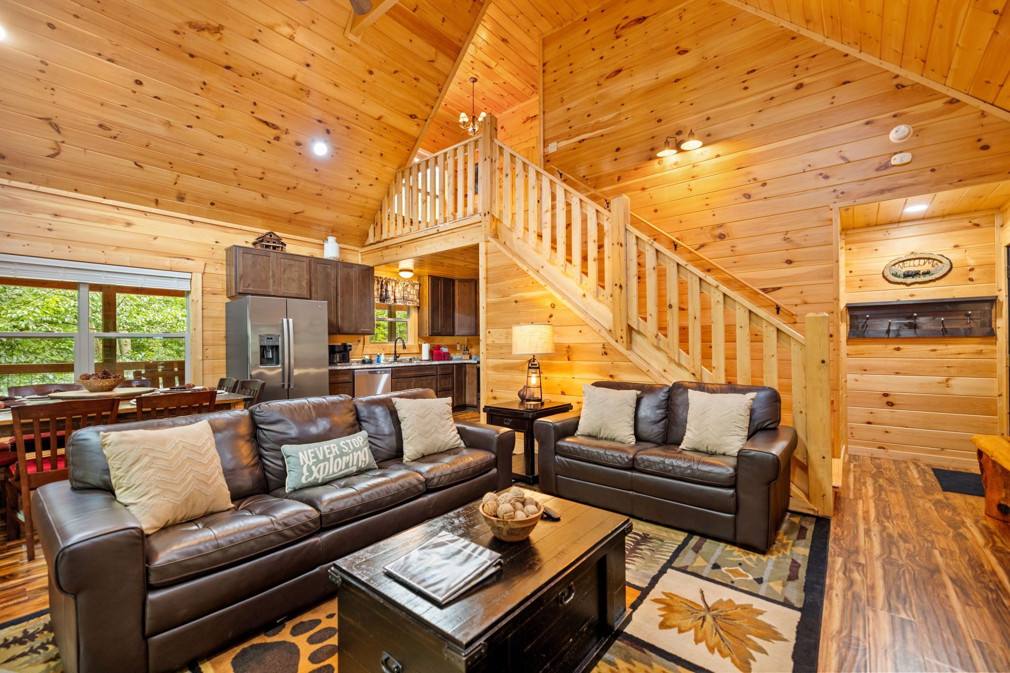 A cozy cabin interior with a living room, kitchen, and a staircase.