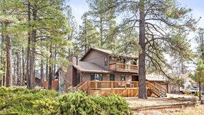 A two-story cabin with a wooden deck and a staircase leading to the upper level. - Spacious Mountain Retreat with Decks & Hot Tub in Kachina Village! (Flagstaff)