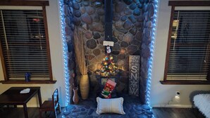 A cozy seating area with a stone wall, a Christmas tree, and a fireplace. - Spacious Mountain Retreat with Decks & Hot Tub in Kachina Village! (Flagstaff)