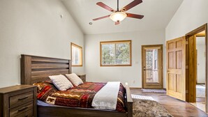 A bedroom with a wooden bed, a ceiling fan, and two windows with blinds. - Spacious Mountain Retreat with Decks & Hot Tub in Kachina Village! (Flagstaff)
