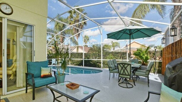 A covered outdoor area with a pool, seating, and a grill. - Maya Beautiful 4 BR Home 10 Minutes to Disney (Kissimmee)