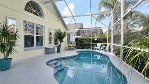 An indoor swimming pool with a glass ceiling, surrounded by potted plants and outdoor furniture. - Maya Beautiful 4 BR Home 10 Minutes to Disney (Kissimmee)