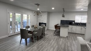 A modern kitchen with white cabinets, a black backsplash, and a dining area with a glass table and chairs. - Luxury 2 Bed 1Bath Monthly. (Las Vegas)