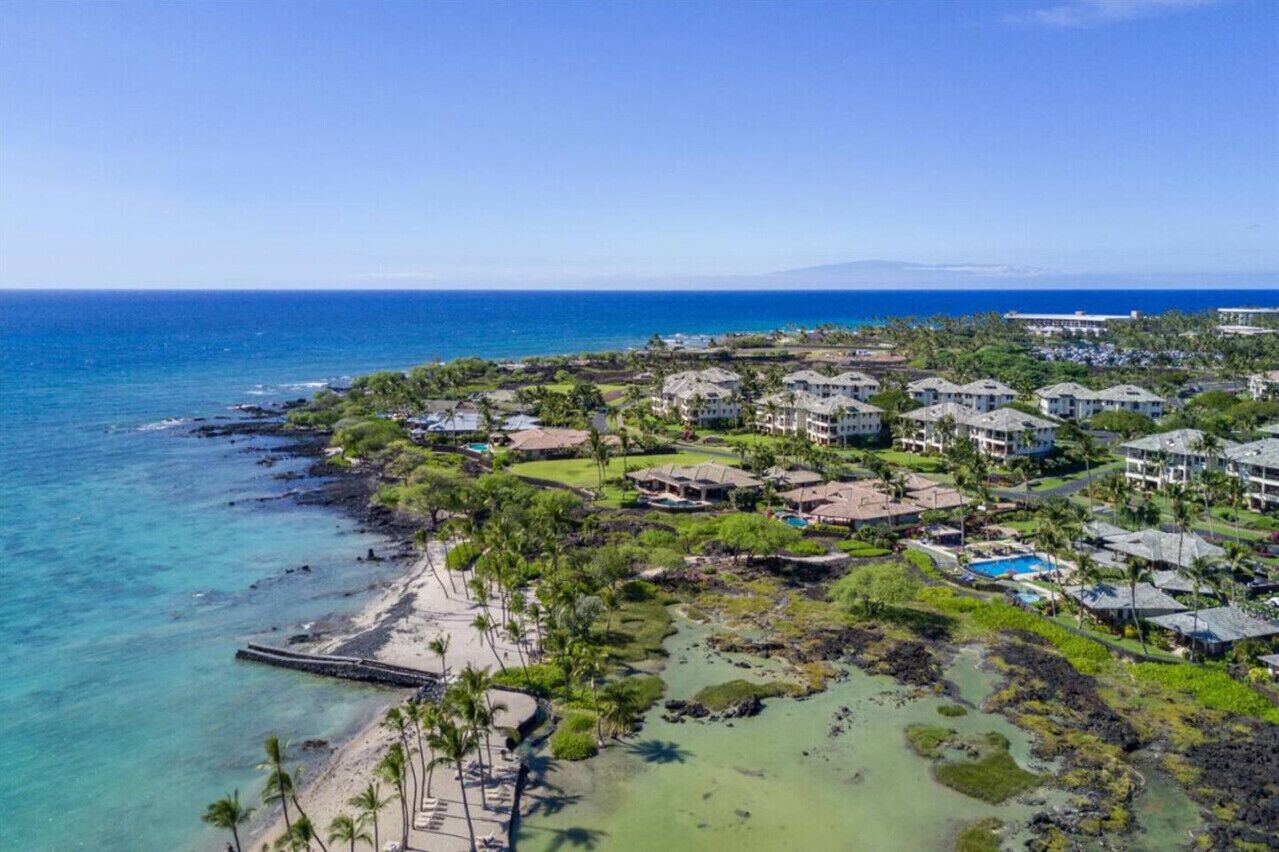 A coastal resort with multiple buildings, a beach, and a clear view of the ocean.