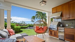 Una cocina con vistas a un jardín tropical, una silla de mimbre y un comedor con mesa.