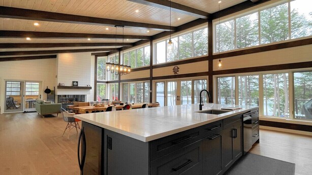 A spacious kitchen with a large island, modern appliances, and large windows offering views of the outdoors.