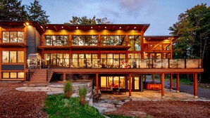 A modern two-story house with large windows, a stone staircase, and a patio area.