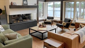 A spacious living room with a fireplace, large windows, and a view of the outdoors.