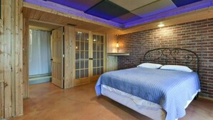 A bedroom with a bed, wooden doors, a brick wall, and a ceiling with blue lighting. - Lakefront 5 Bedroom, 3 Bath Cabin on Tablerock Lake, PONTOON available to rent! (Eagle Rock)