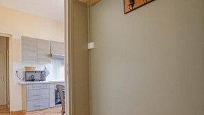 A room with a wooden bench, a kitchen in the background, and a wooden shelf with decorative items. - L'Idéal - SAINTE SAVINE (SAINTE SAVINE)