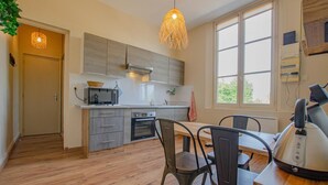 A modern kitchen with grey cabinets, a microwave, an oven, and a dining table with chairs. - L'Idéal - SAINTE SAVINE (SAINTE SAVINE)