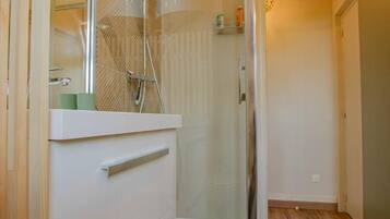 Une salle de bain moderne avec une douche à parois de verre, un meuble-lavabo blanc et un plancher en bois.
