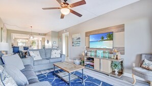 A modern living room with a grey sofa, a coffee table, and a TV mounted on the wall.