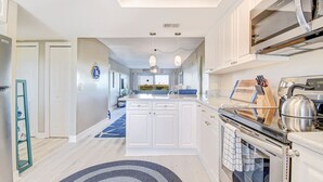 A modern kitchen with white cabinets, a built-in oven, and a stainless steel kettle.