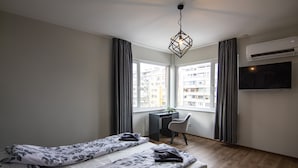 Un dormitorio con dos camas, un escritorio, una silla y un televisor.