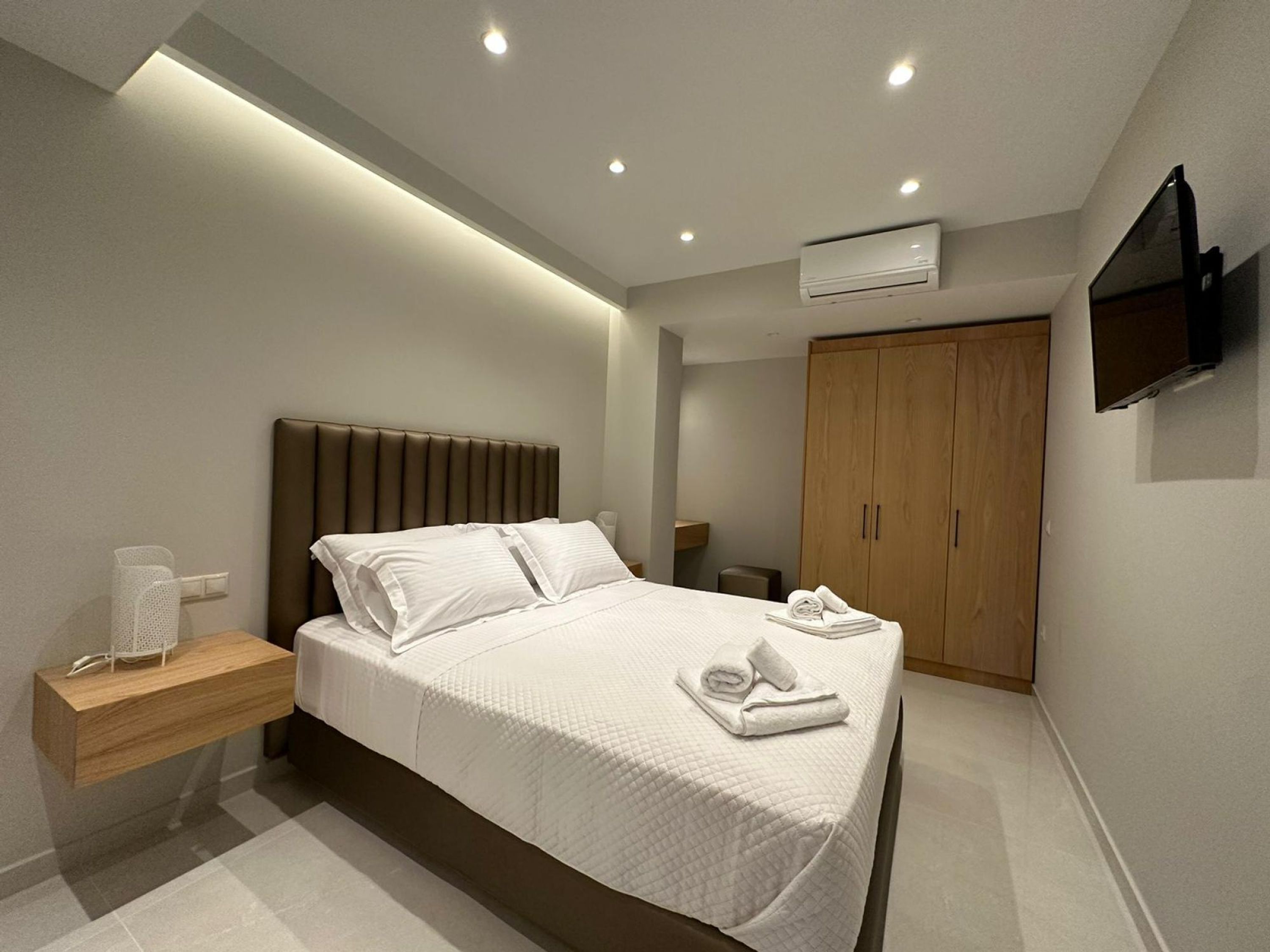 Una camera d'albergo moderna con un letto grande, un comodino e un televisore montato a parete.