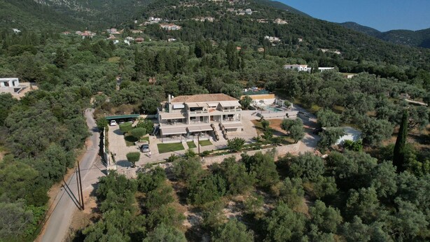 A modern two-story house with a swimming pool, surrounded by dense forest and hills. - Elpida Luxury Apartments & Suites (Lefkada)