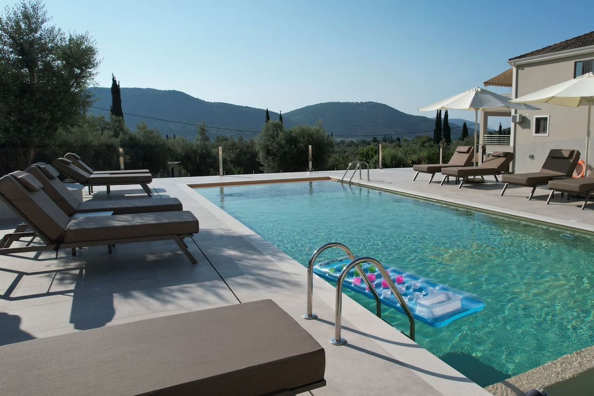 Une piscine avec des chaises longues, un jouet flottant et une vue sur les montagnes en arrière-plan.