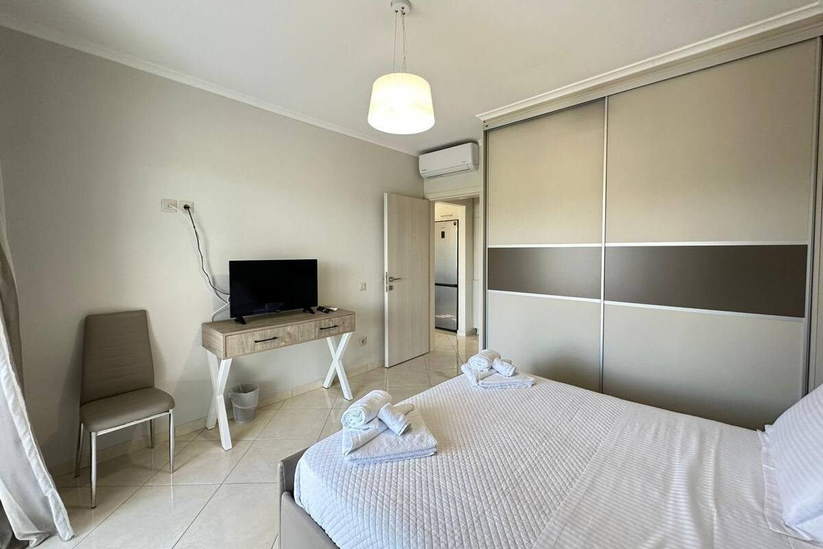 Une chambre d’hôtel moderne équipée d’un lit, d’un bureau avec une télévision, d’une chaise et d’une armoire.