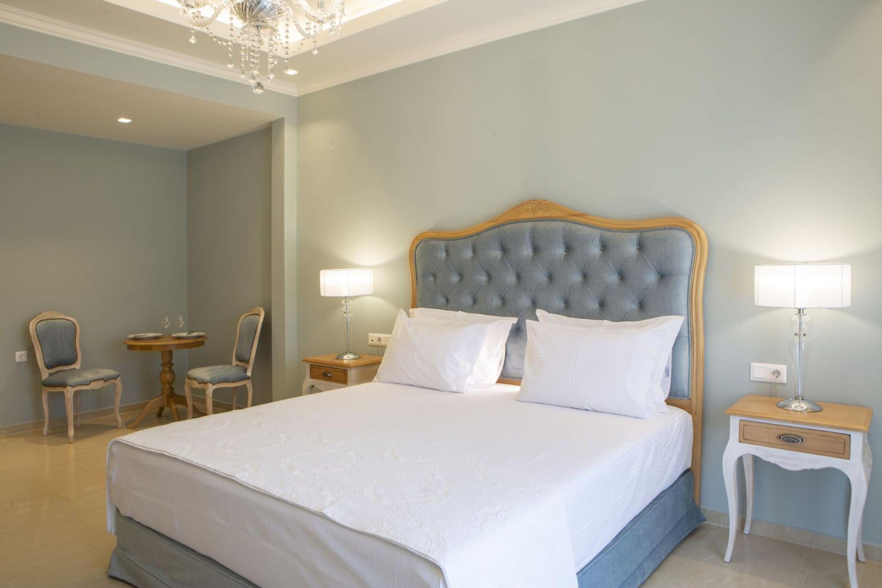 Une chambre à coucher bien aménagée, avec un grand lit, deux tables de chevet dotées de lampes et deux chaises.