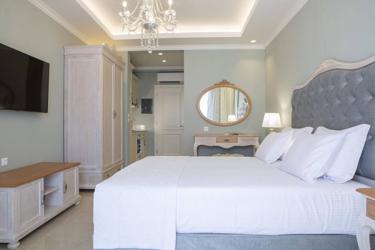 Een slaapkamer met een groot bed, een dressoir, een kaptafel en een televisie.