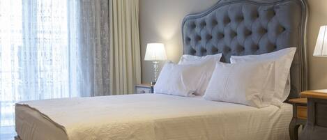 A neatly made bed with a tufted headboard, white linens, and a bedside lamp.