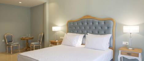 A neatly arranged bedroom with a large bed, two bedside tables with lamps, and two chairs.