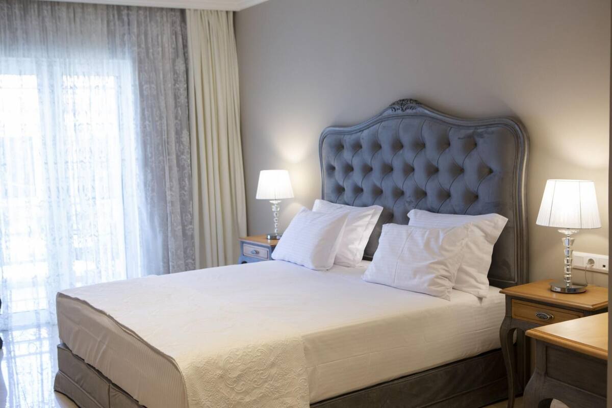 Een hotelkamer met een groot bed, twee nachtkastjes en een raam met gordijnen.