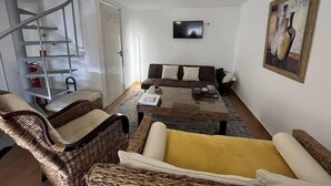 Una sala de estar con un sofá, sillas, una mesa de centro, un televisor y un cuadro.