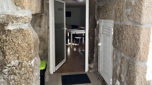 Un estrecho pasillo de paredes de piedra que conduce a un cuarto con una mesa y sillas para comer.