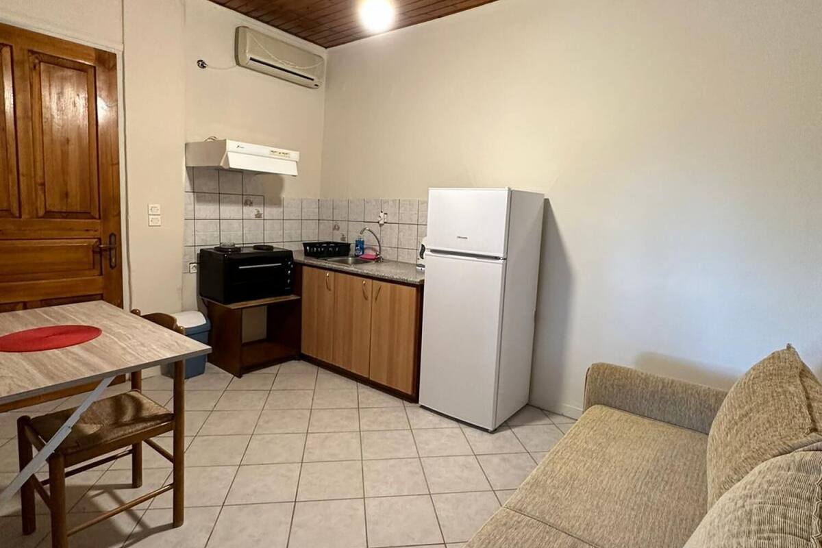 A compact kitchen with wooden cabinets, a white refrigerator, and a tiled floor.