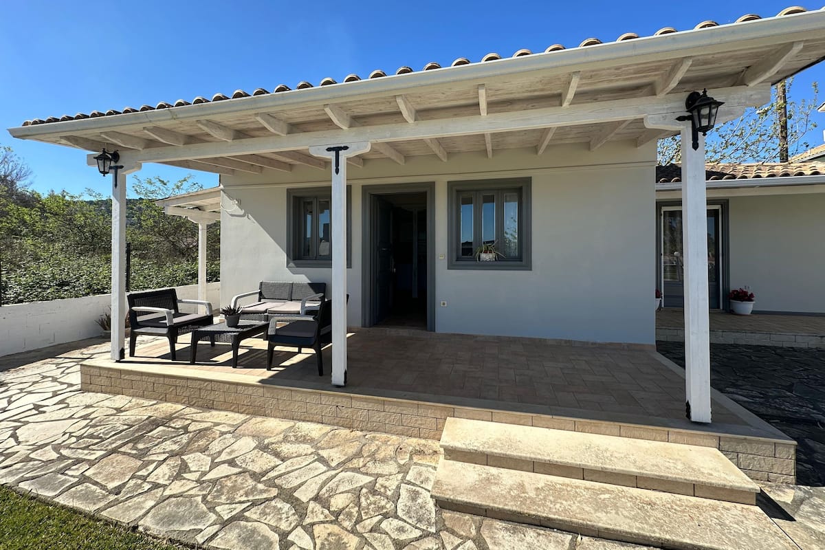 A covered patio area with stone flooring and outdoor furniture.