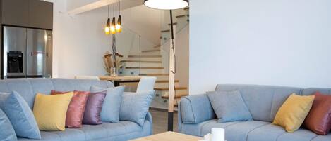Un salon moderne avec deux canapés gris, une table basse en bois et une lampe suspendue.