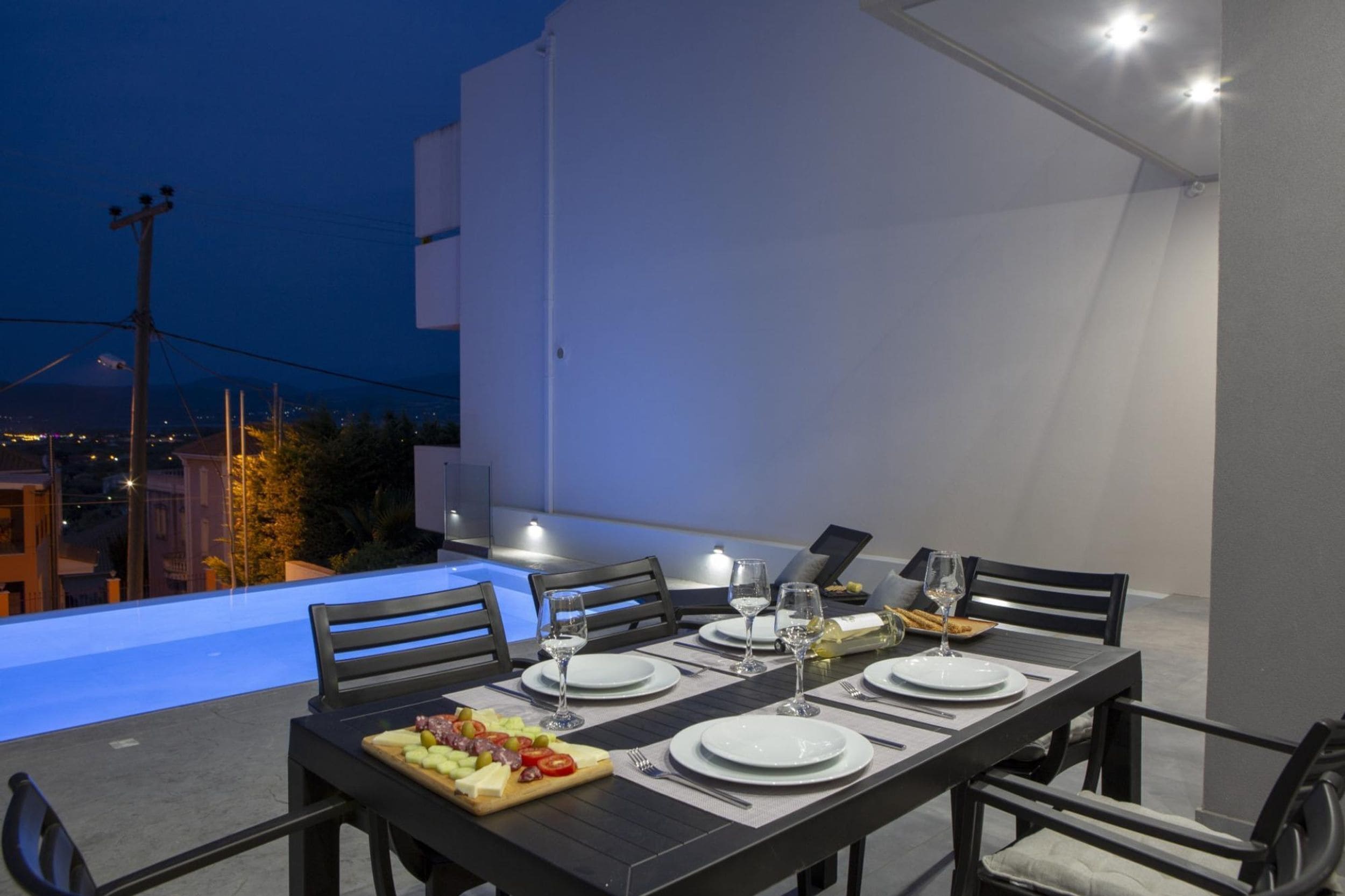 A dining table set for four with a view of the city at dusk.
