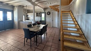 A spacious kitchen with a central island, a dining area with a wooden table and chairs, and a wooden staircase leading to an upper level. - Eris Villa - Amazing View In Lefkada (Lefkada)