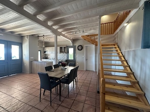 A spacious kitchen with a central island, a dining area with a wooden table and chairs, and a wooden staircase leading to an upper level. - Eris Villa - Amazing View In Lefkada (Lefkada)