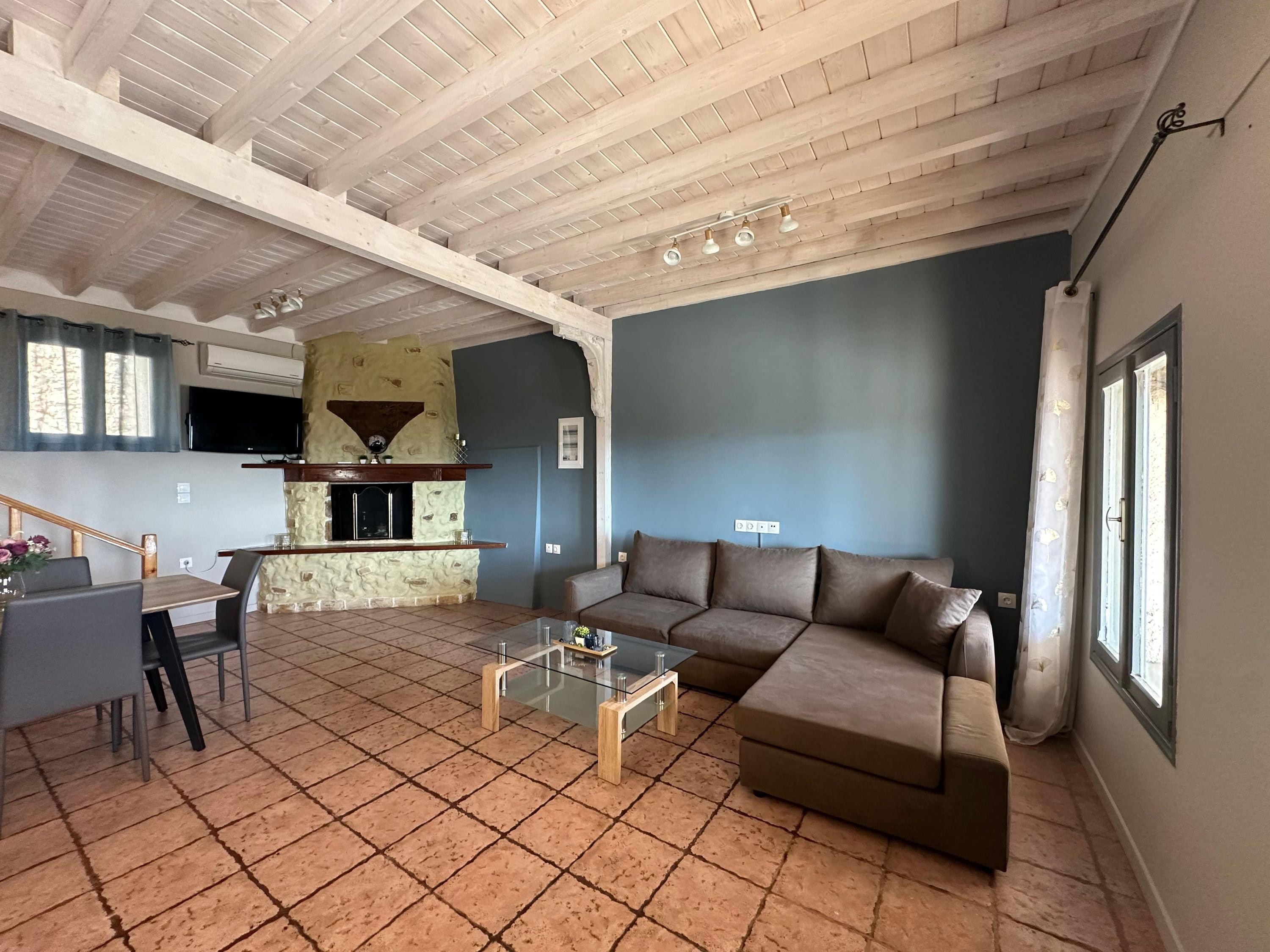 A living room with a stone fireplace, a sofa, a coffee table, and a dining area with a table and chairs.