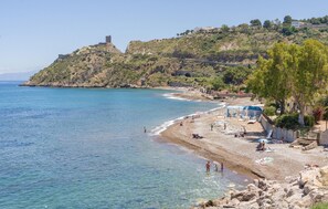 A beach with clear blue waters, rocky terrain, and a hill with a tower. - 2 bedroom cozy home in Trabia (Trabia)