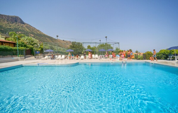 A swimming pool with clear blue water, surrounded by lounge chairs and umbrellas. - 2 bedroom cozy home in Trabia (Trabia)