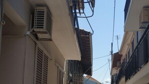 Una calle estrecha flanqueada por edificios, con balcones y unidades de aire acondicionado.