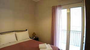 Habitación de hotel con cama, mesita de noche, lámpara, ventana con cortinas y aire acondicionado.