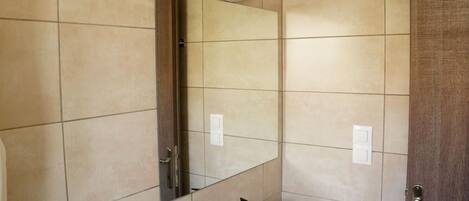 A modern bathroom with a large mirror, a bathtub, and a vanity with a sink.