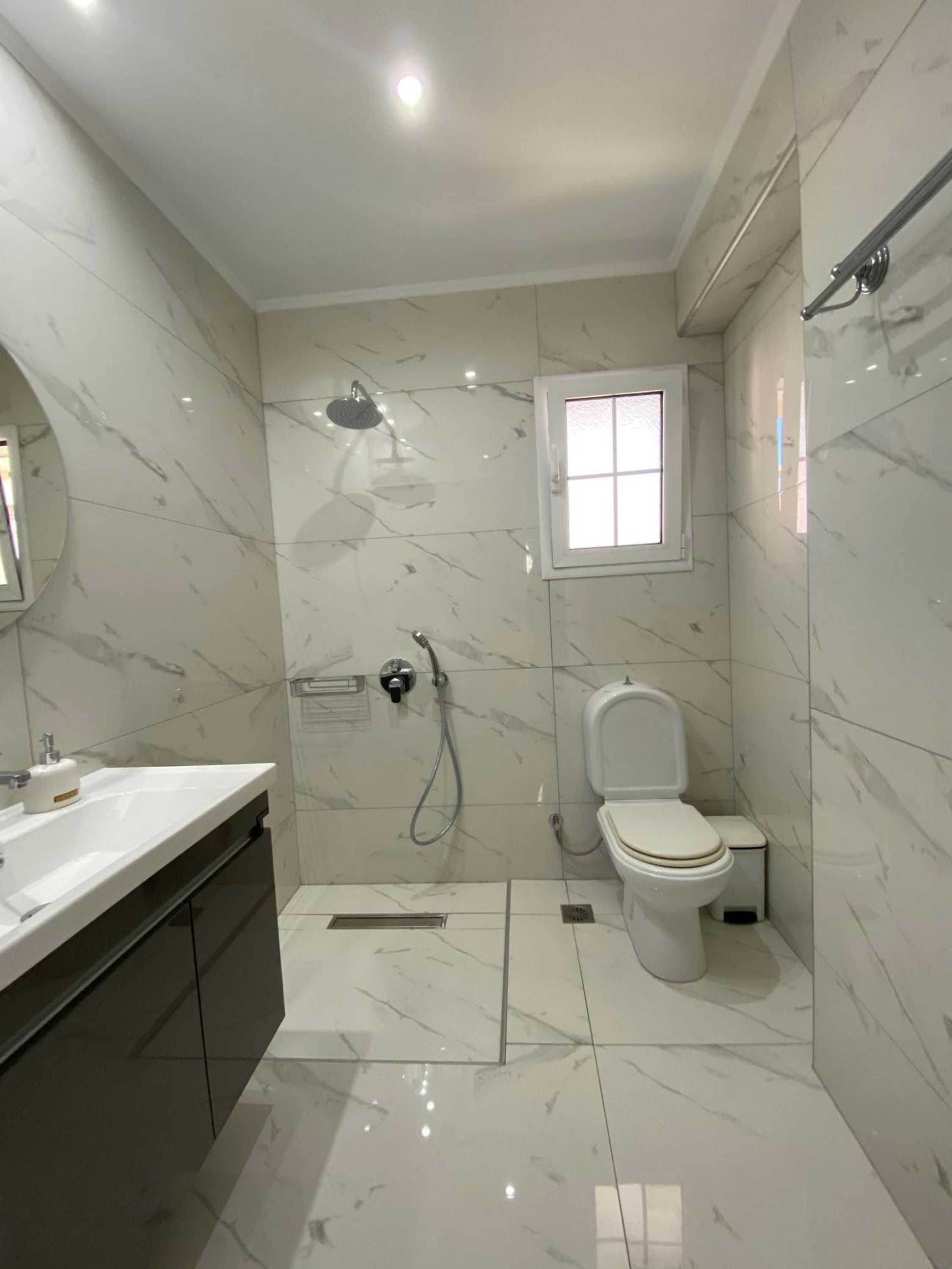 A modern bathroom with a shower, toilet, and vanity.