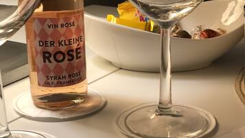 Eine Flasche Der Kleine Rose Wein und ein Weinglas auf einem Tisch mit einer Schale Snacks.